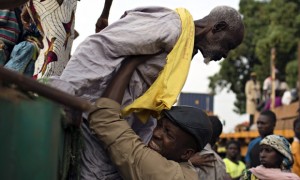 Father Bernard Kenvi helps a Muslim man climb down from an open truck in Bossemptele